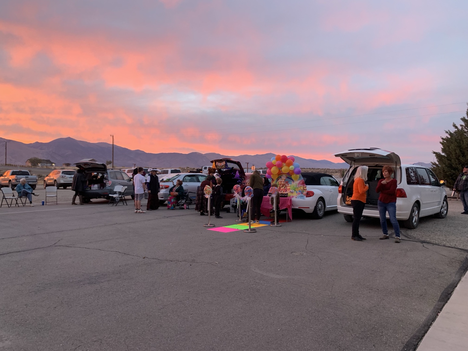 Families visiting decorated vehicles during the community Trunk or Treat at sunset